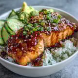 Quick Teriyaki Salmon Bowl featuring tender salmon, crisp cucumber, avocado, and carrots over fluffy rice with sesame garnish.
