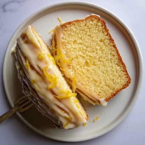 A golden Lemon Pound Cake slice on a plate, ready to serve with fresh blueberries and a hot cup of coffee.