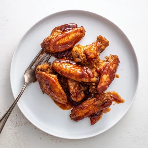 Crispy golden Honey BBQ Chicken Wings coated in sticky, smoky barbecue glaze on a platter.