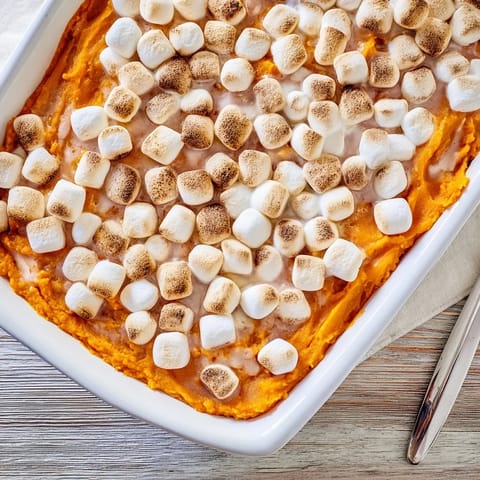 Sweet potato casserole with crunchy pecan streusel topping sits beside festive holiday dinner rolls.