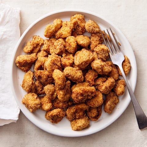 Homemade extra-crispy Popcorn Chicken bites fresh from the fryer, glistening on a wire cooling rack.