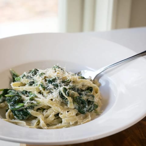 Fresh baby spinach wilted into rich garlic cream sauce, tossed with al dente fettuccine pasta for a comforting meal.  