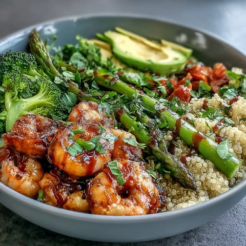 Colorful Detox Buddha Bowl with Shrimp and Quinoa topped with roasted asparagus, red cabbage, tomatoes, and a drizzle of tangy balsamic dressing.