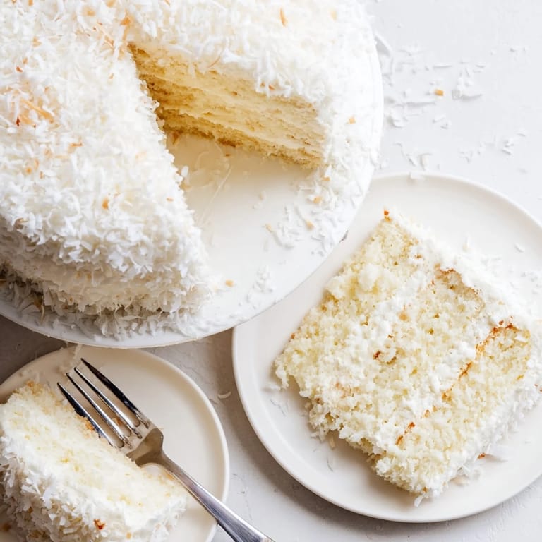 Freshly frosted Coconut Cake with billowy meringue, ready for a celebratory dessert table.
