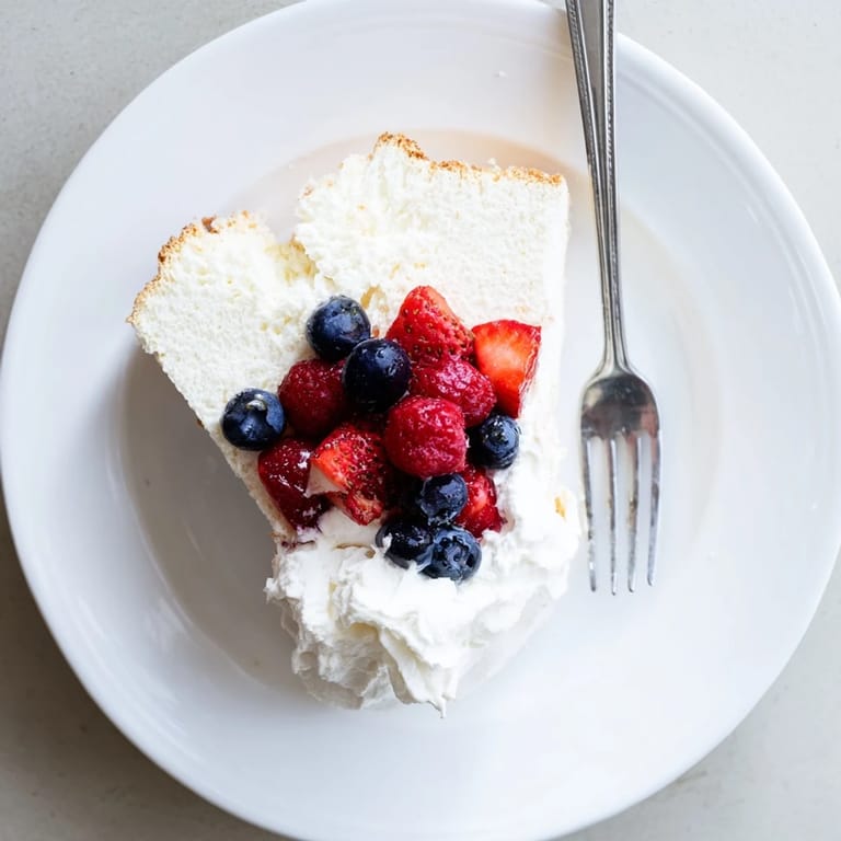 Cooling homemade angel food cake on a wire rack, showcasing its tall, golden crown and light texture.