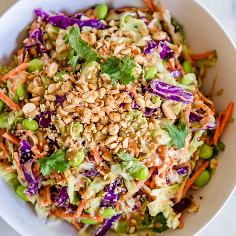 Close-up of a fresh Crunchy Thai Peanut Salad with crunchy vegetables, edamame, and a glossy peanut dressing, served in a white ceramic bowl.