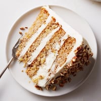 Three layers of Southern Hummingbird Cake are stacked with cream cheese frosting and topped with toasted pecans.