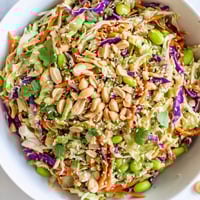 A vibrant Crunchy Thai Peanut Salad features shredded purple cabbage, carrots, and edamame, tossed in a creamy peanut dressing and topped with chopped roasted peanuts.