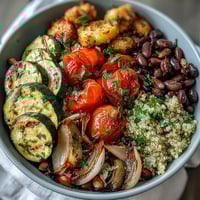 Bright and colorful Veggie and Quinoa Power Bowl topped with crunchy almonds and pumpkin seeds on a rustic wooden table.