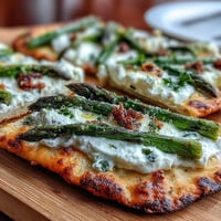 A golden flatbread topped with roasted asparagus, creamy burrata, and a sprinkle of fresh lemon zest.  
