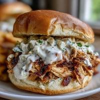 Smoked pulled chicken piled high on soft buns, topped with tangy Alabama-style white BBQ sauce and crunchy coleslaw.  